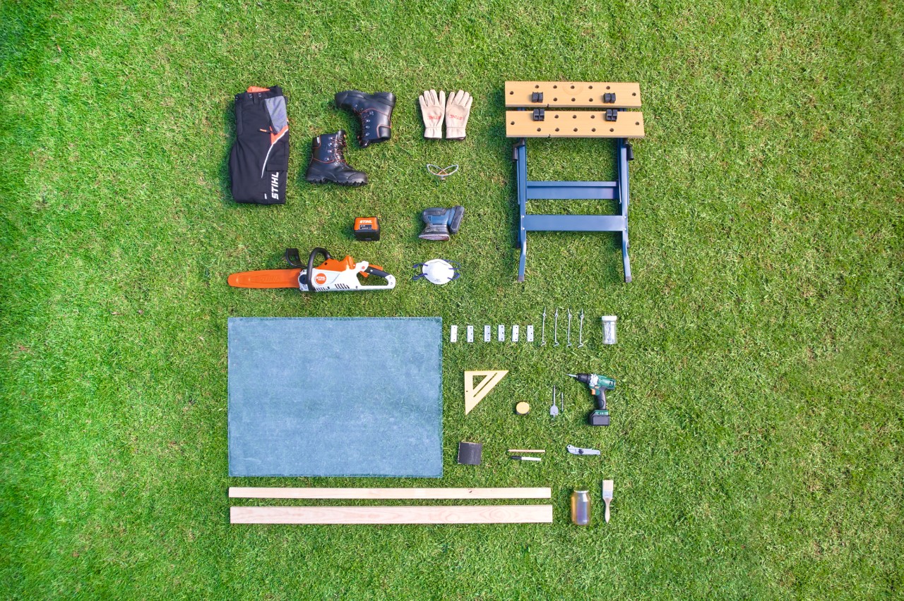 Materiaal, gereedschap en veiligheidsuitrusting voor een zelfgemaakte afdekking voor een verhoogd bed liggen in een vierkant op het gazon