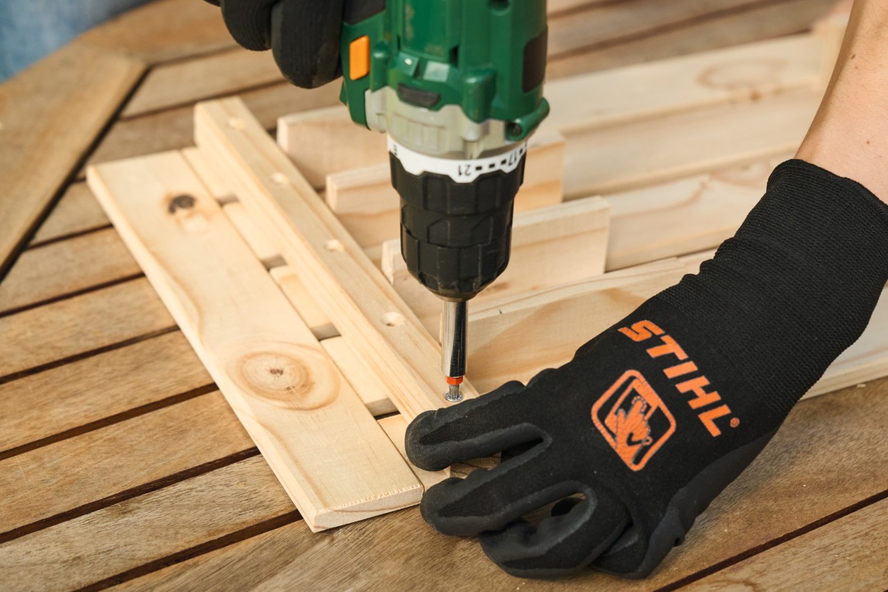 Close-up van iemand die met STIHL veiligheidshandschoenen aan de gaten voorboort