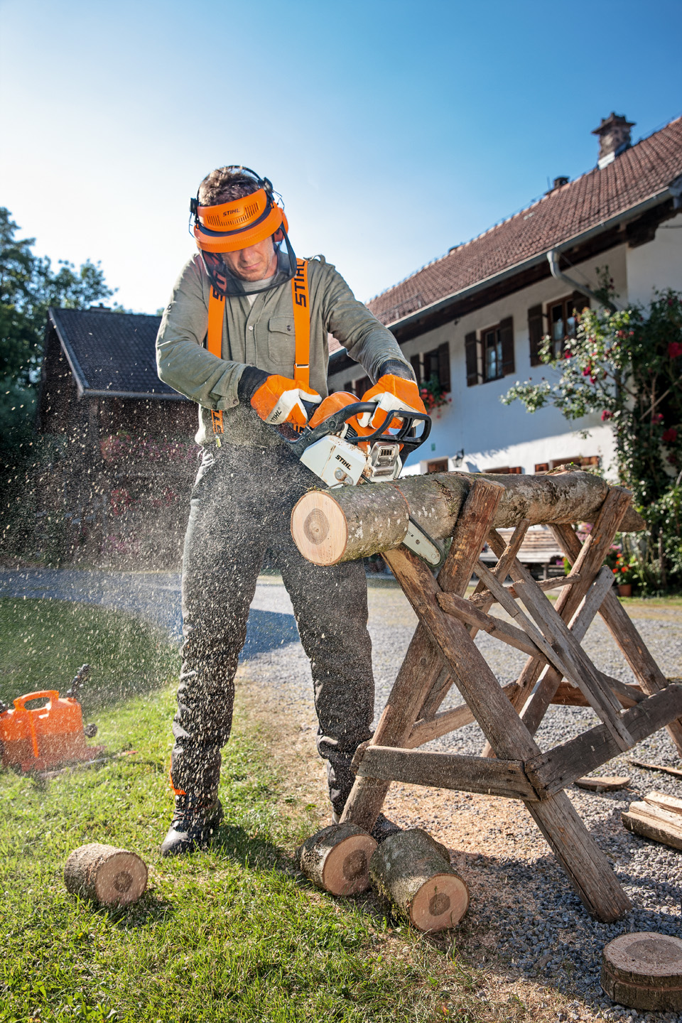 Man met veiligheidskledij zaagt met een STIHL MS 170 benzinekettingzaag een stuk van een boomstam op een zaagbok