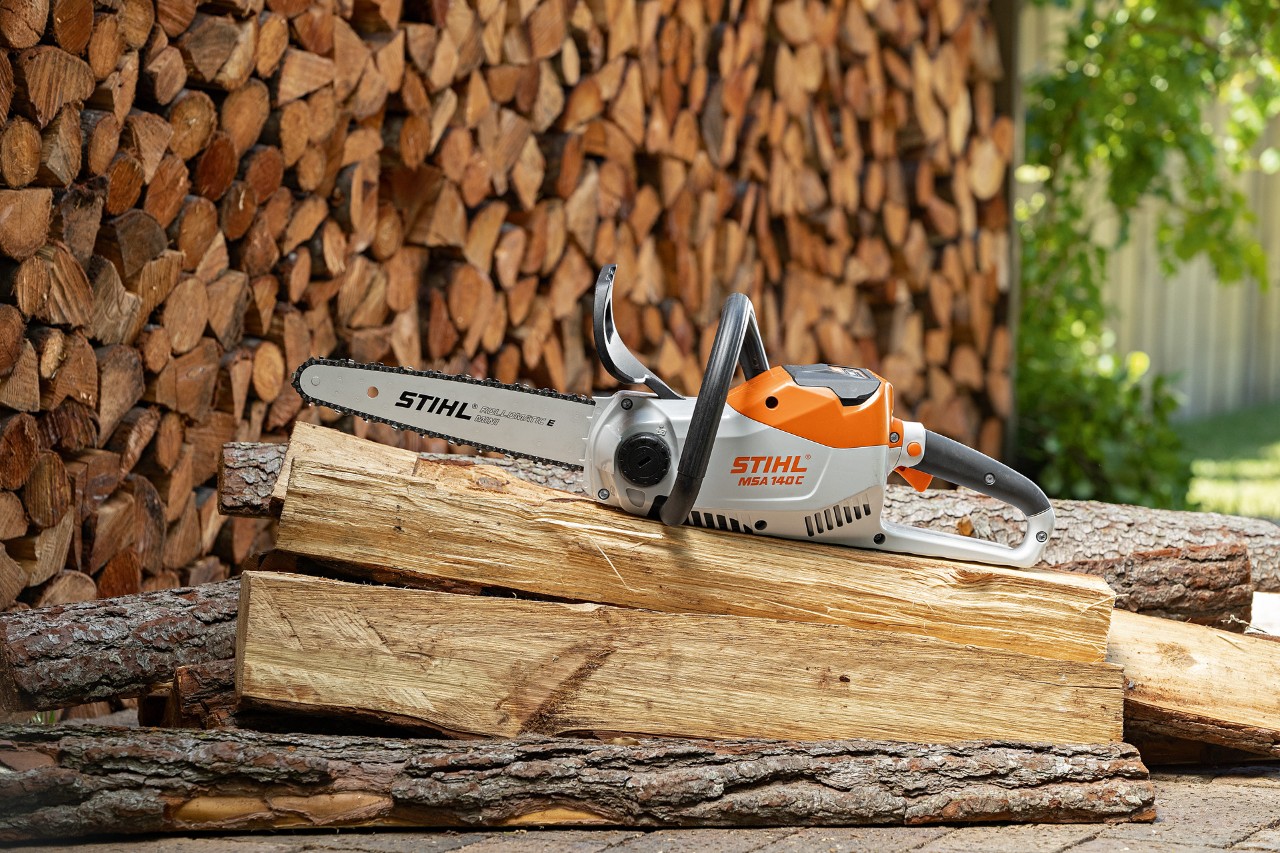 STIHL accu-kettingzaag MSA 140 C-B bij een stapel lange stukken gekloofd hout