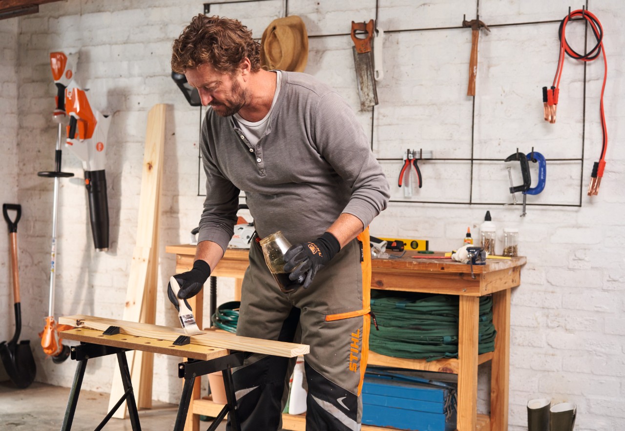 Man aan een werkbank oliet houten onderdelen voor een plantentafel