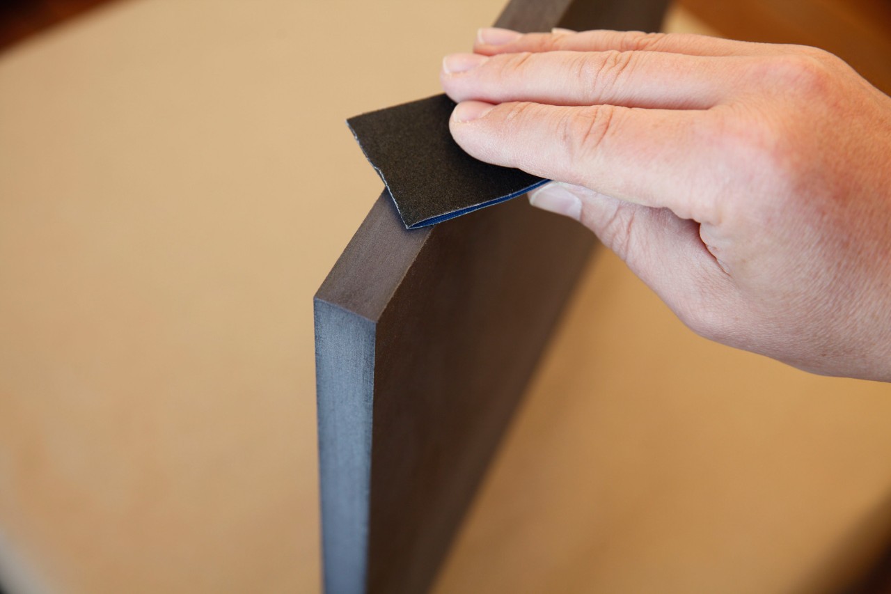  DIY-kruk van een boomstam: close-up van de snijrand van een MDF-plaat die wordt geschuurd