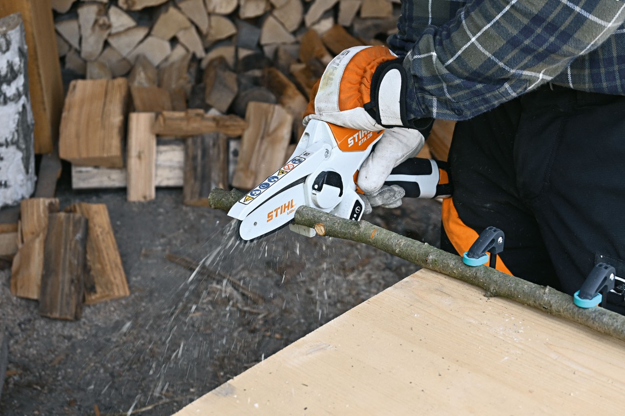 Close-up van een persoon die een tak in stukken verdeelt met de STIHL GTA 26 accusnoeizaag