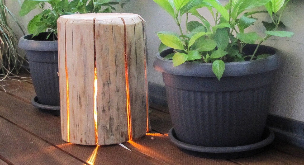 Houten lamp met theelicht in de vensterbank, naast potplanten.