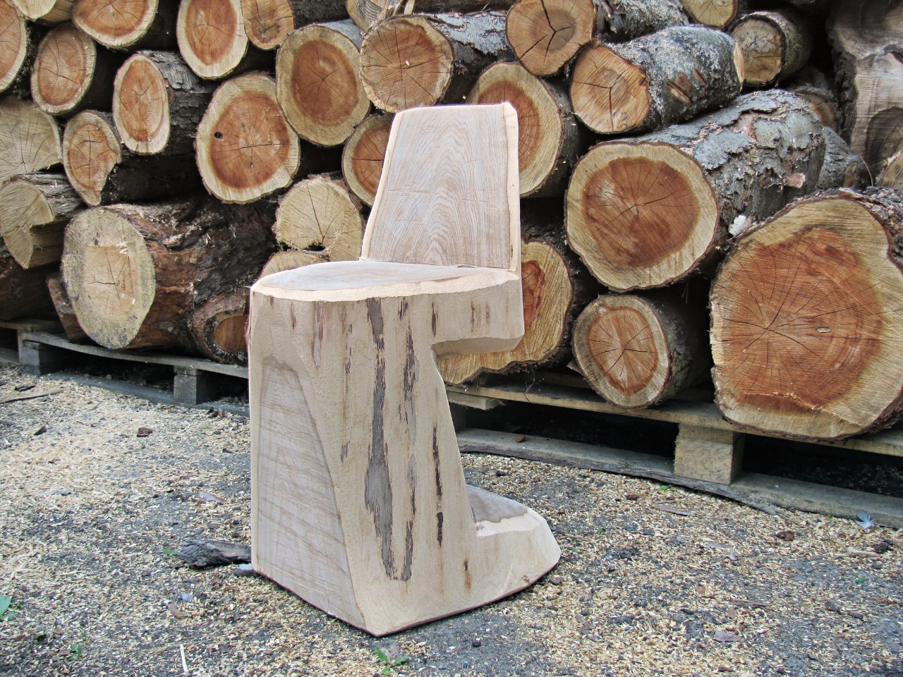 Zelfgemaakte houten stoel voor een stapel brandhout.