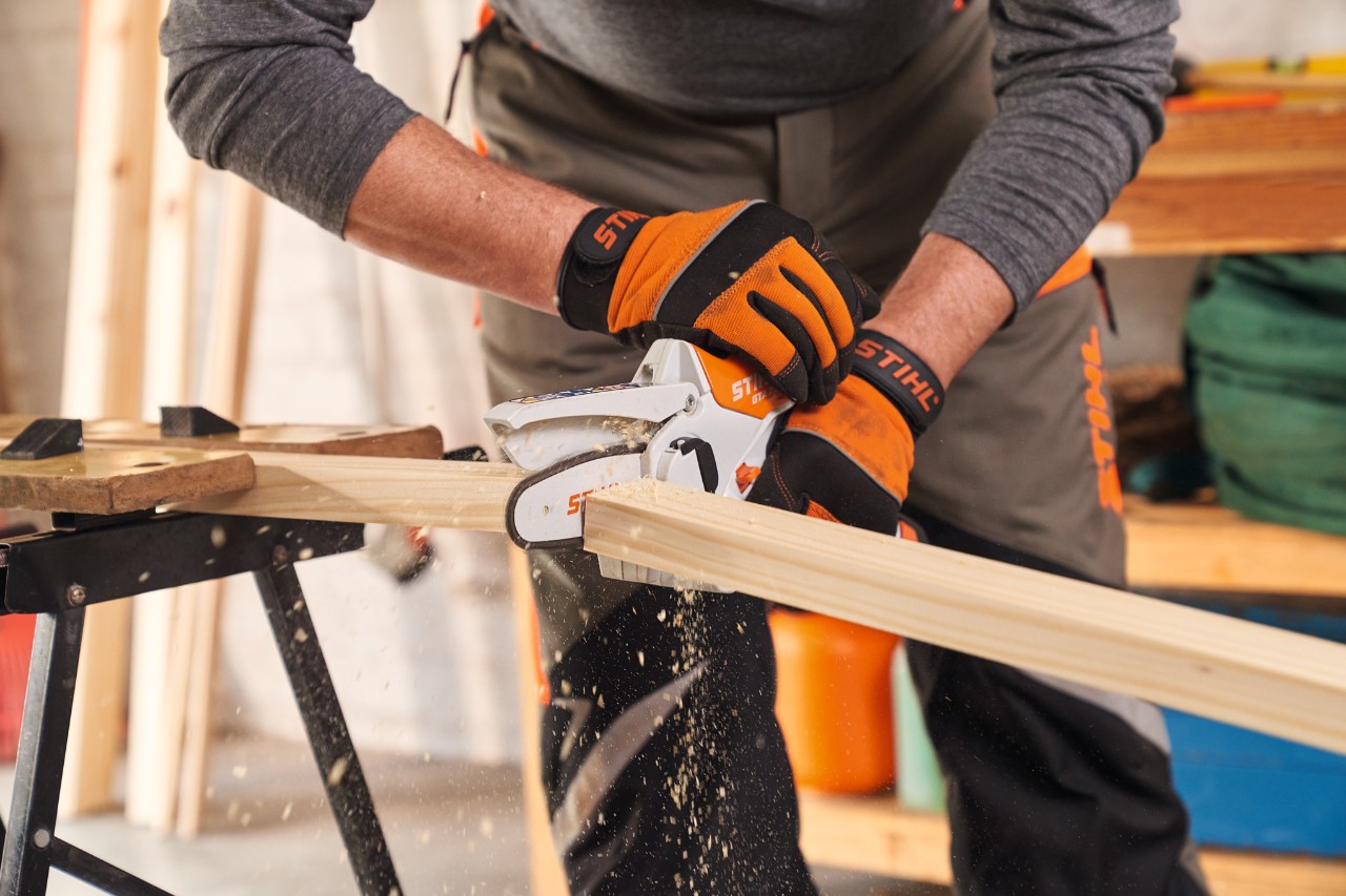 Persoon met veiligheidshandschoenen STIHL Function Protect zaagt framebalken voor bescherming tegen inkijk af met de snoeizaag STIHL GTA 26
