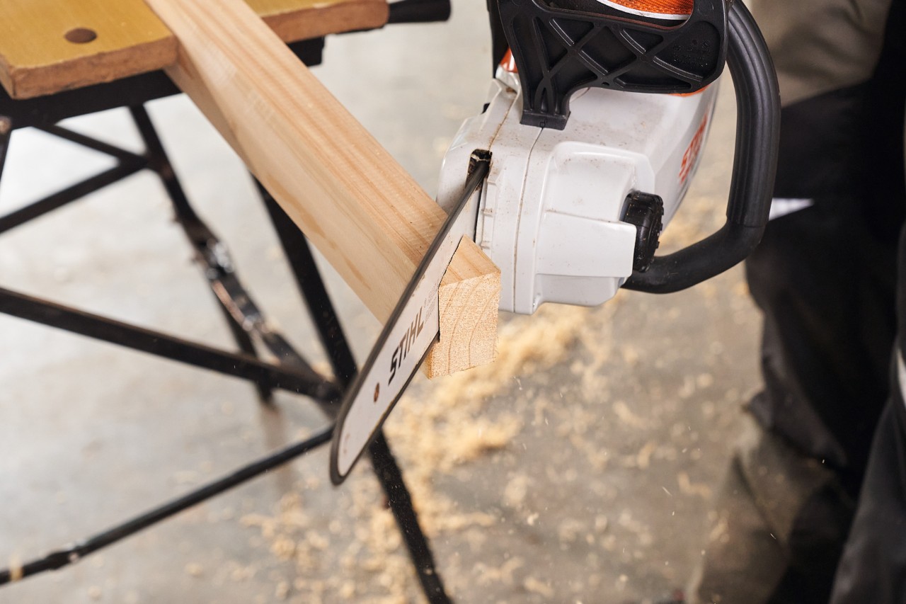 Met een STIHL MSA 140 accukettingzaag worden de vierkante palen voor de voetstukken van een schutting tegen inkijk op maat gezaagd    