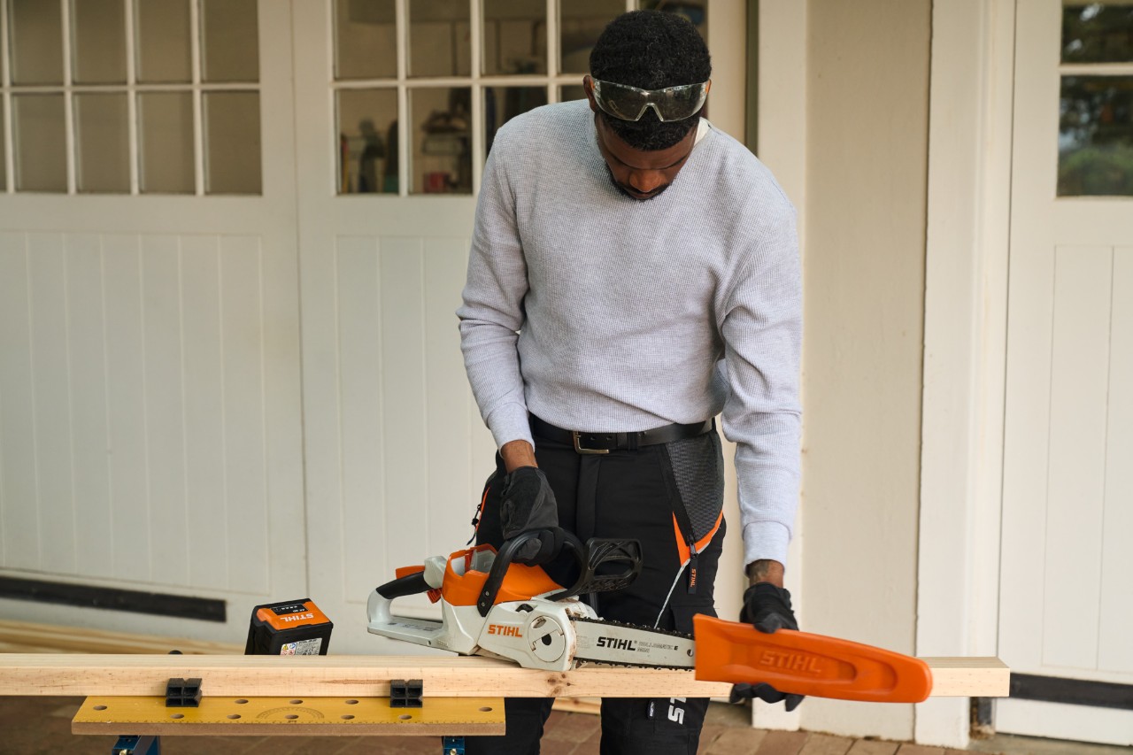 Een man staat voor een werkplaats en verwijdert de bescherming van een STIHL MSA 70 accukettingzaag 