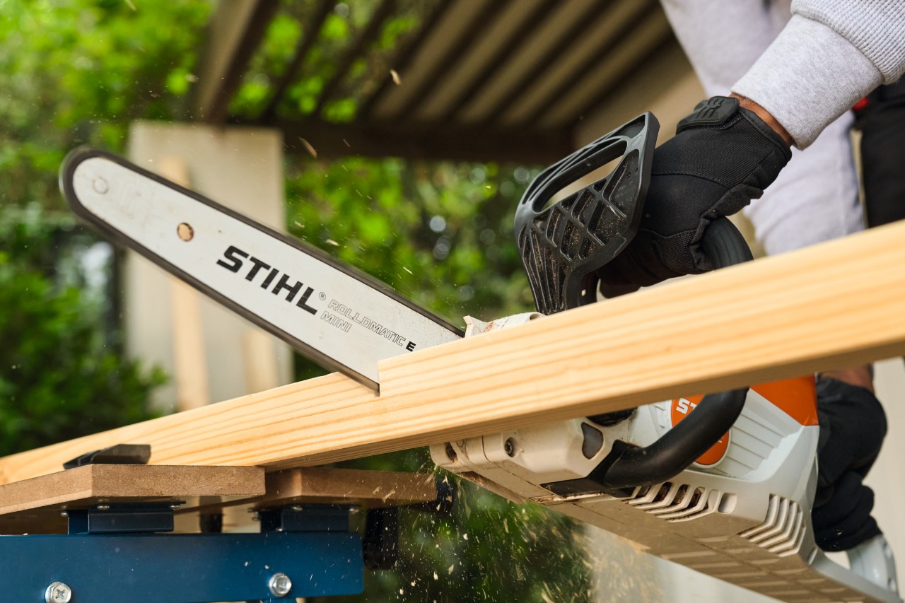 Een man zaagt een zijlat voor een voetbaldoel met een STIHL MSA 70