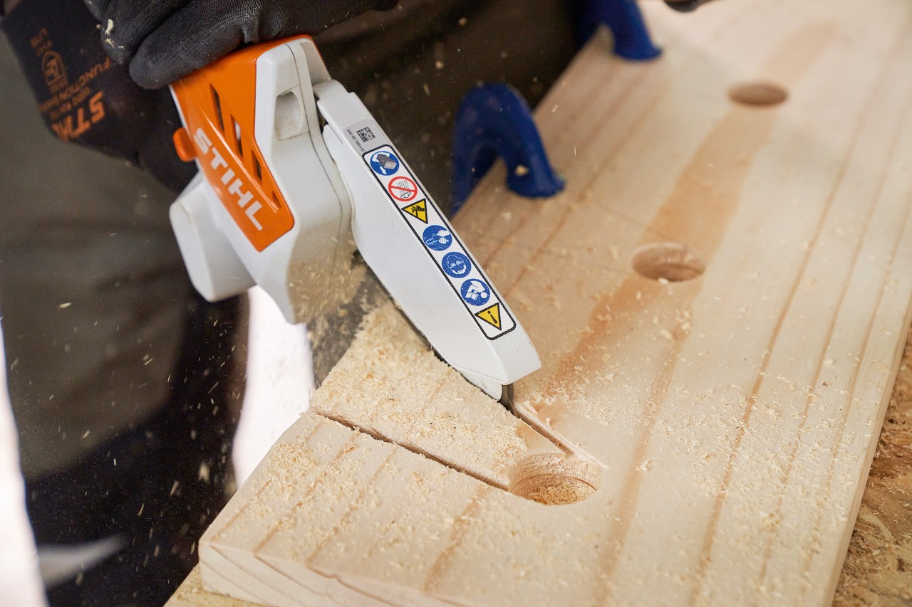 Iemand zaagt met de STIHL GTA 26 accusnoeizaag uitsparingen uit een houten plank