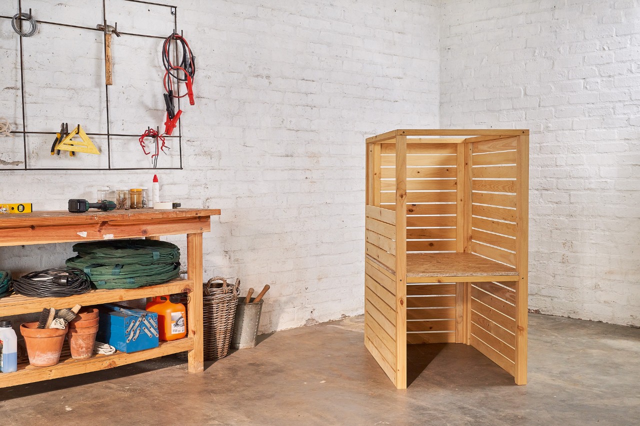 Het basisframe van een zelfgebouwde berging voor de grasmaaier in een garage 