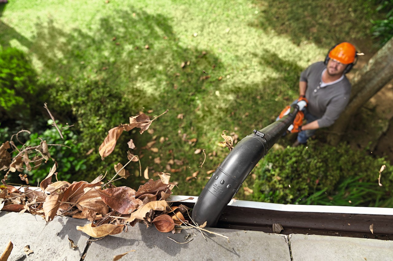 Man maakt dakgoot schoon met STIHL dakgootreinigingsset