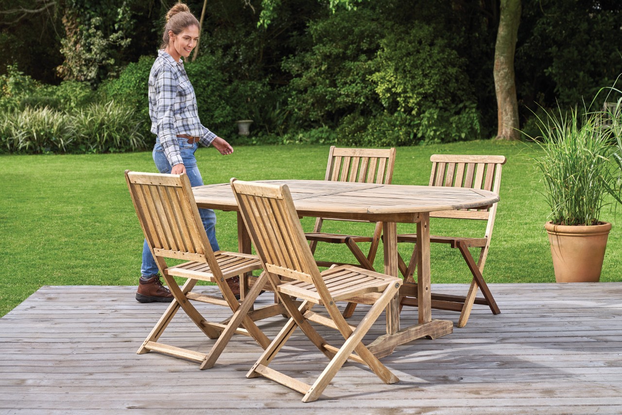 Een vrouw bij een schone set houten tuinmeubelen, met daarnaast een STIHL RE 130 Plus hogedrukreiniger