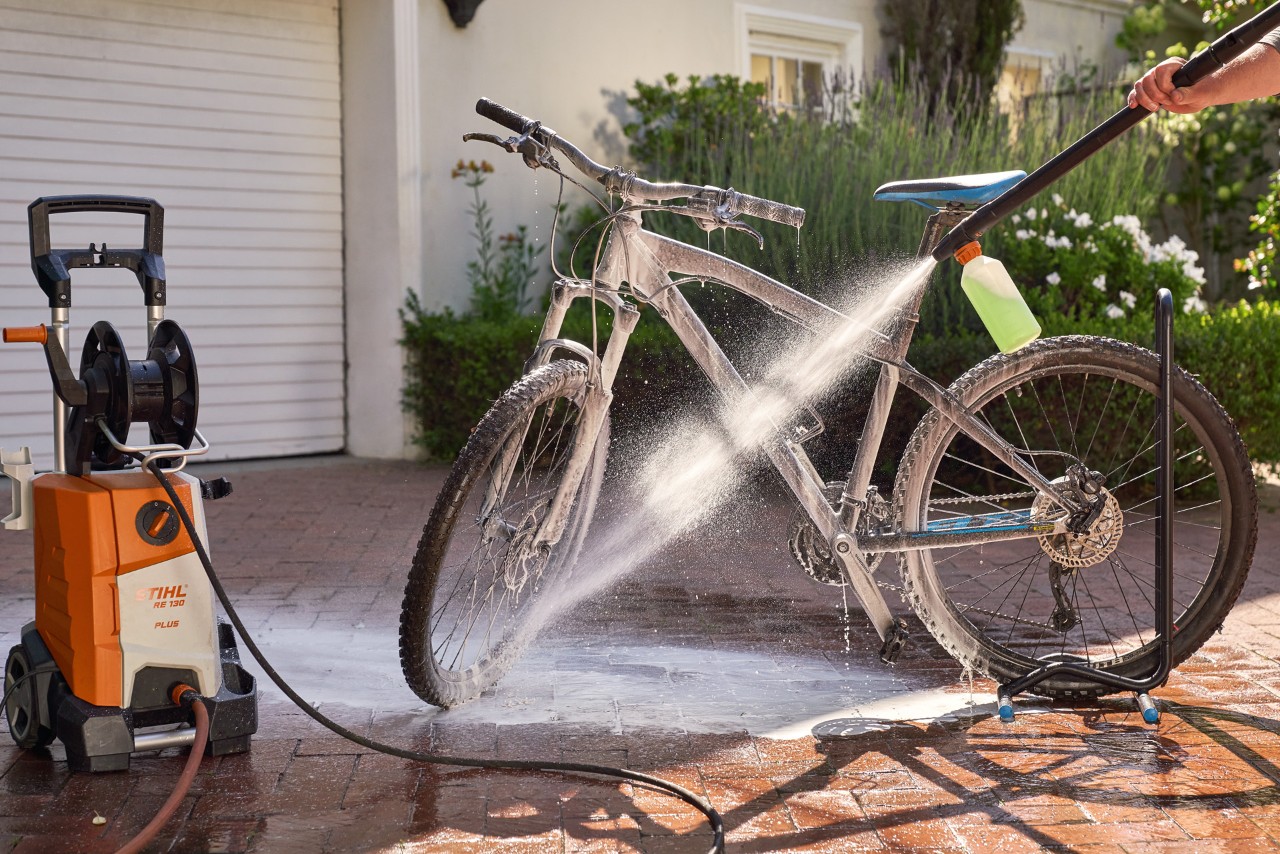 Een fiets wordt gereinigd met een STIHL RE 130 Plus hogedrukreiniger met schuimsproeier en voertuigshampoo