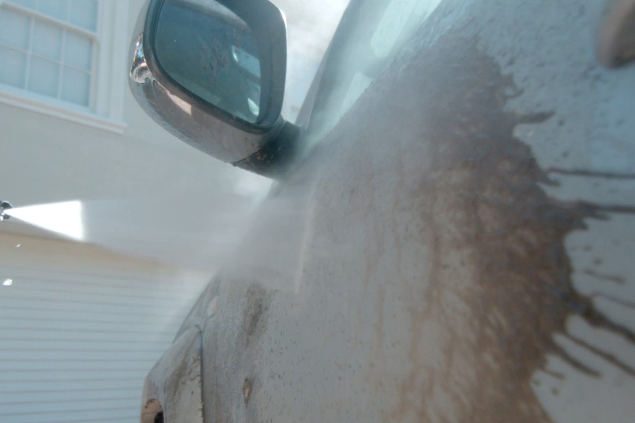 Close-up van een vuile autodeur die wordt gewassen met een hogedrukreiniger