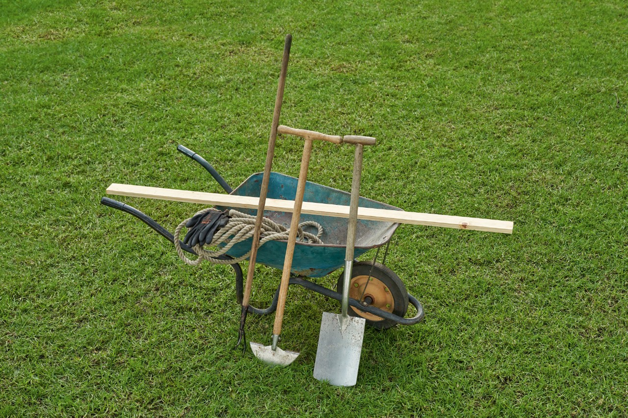 Close-up: gereedschap voor het afsteken van de Engelse gazonrand: kruiwagen, spade, kantensteker. 