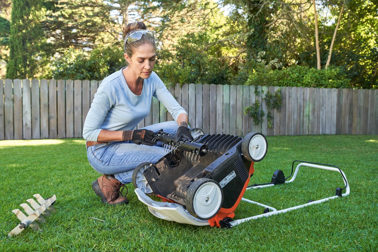 Vrouw met veiligheidsbril en werkhandschoenen verwisselt verticuteereenheid van de STIHL RLA 240 accuverticuteermachine 