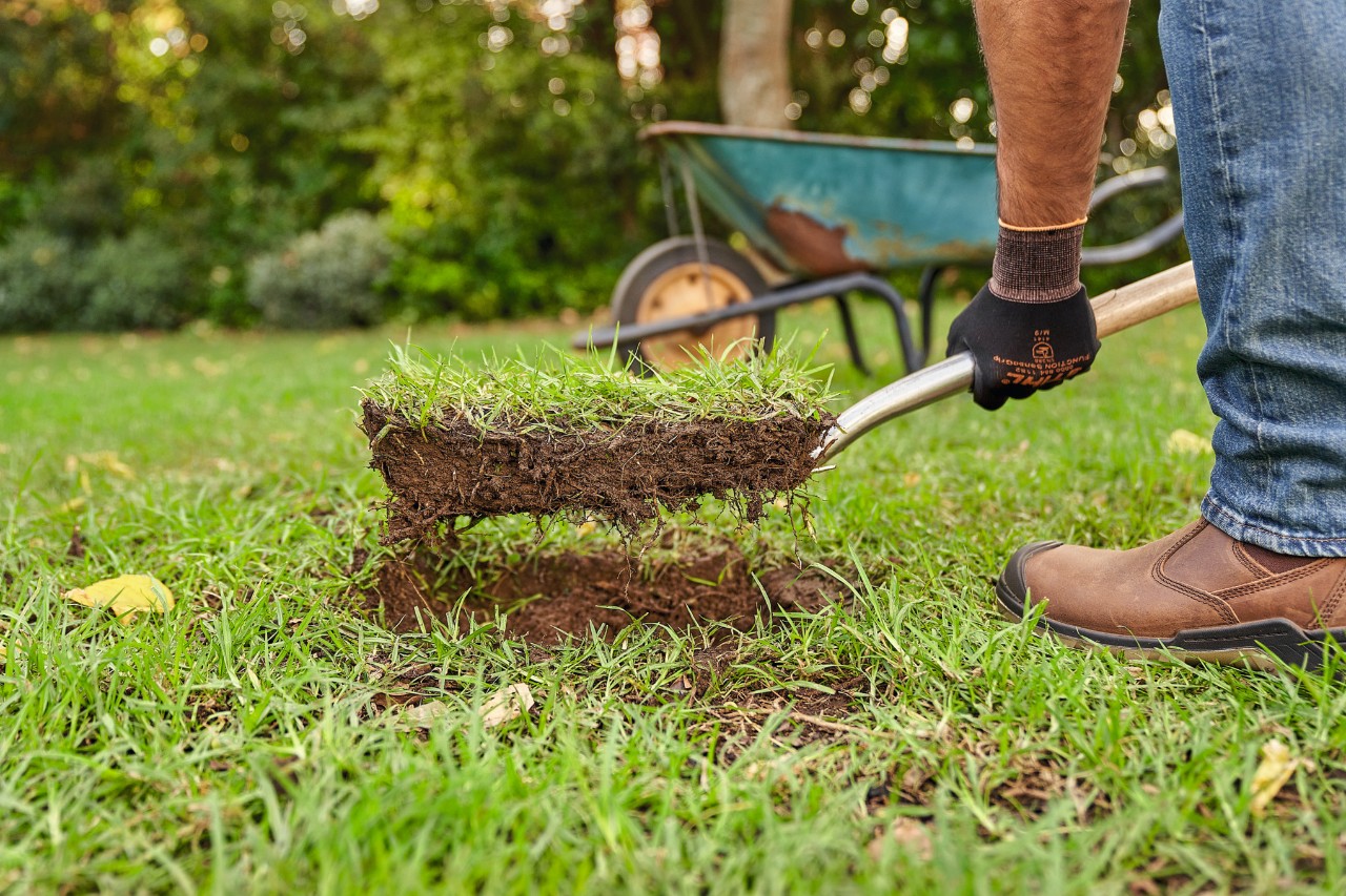 Close-up van iemand die met een spade de grasmat verwijdert