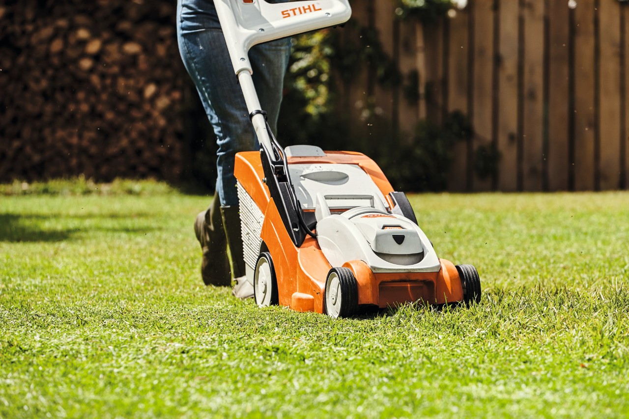 Close-up van iemand die met een STIHL grasmaaier een gazon maait 