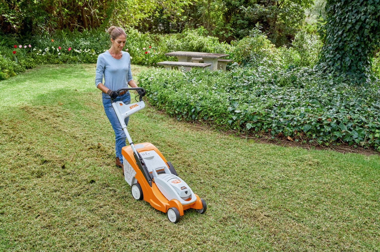 Een vrouw maait haar gazon met een STIHL RMA 339 C accugrasmaaier om het gras voor te bereiden op vernieuwing