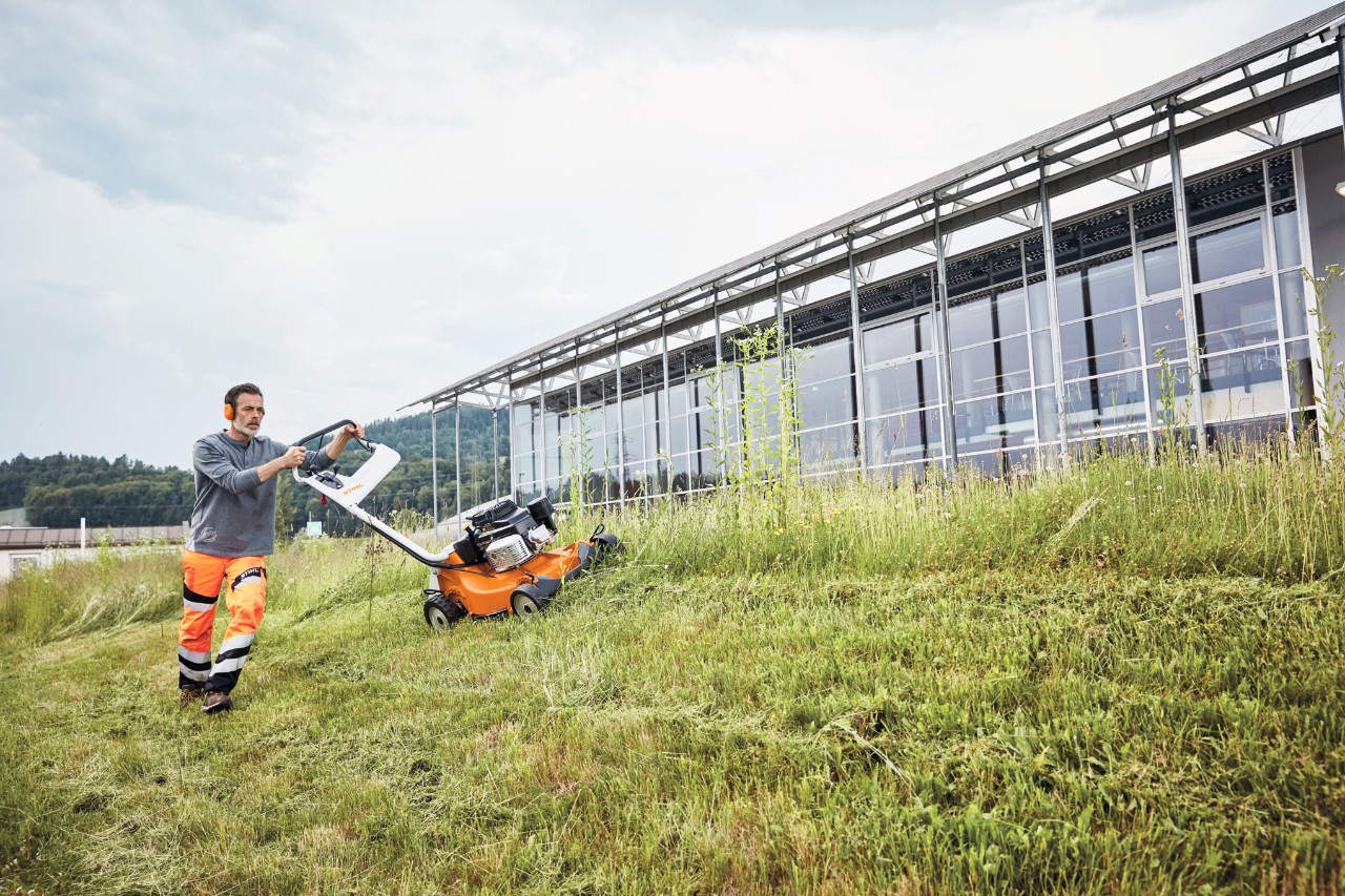 Een man maait op een helling met een STIHL RM 756 GC benzinegrasmaaier