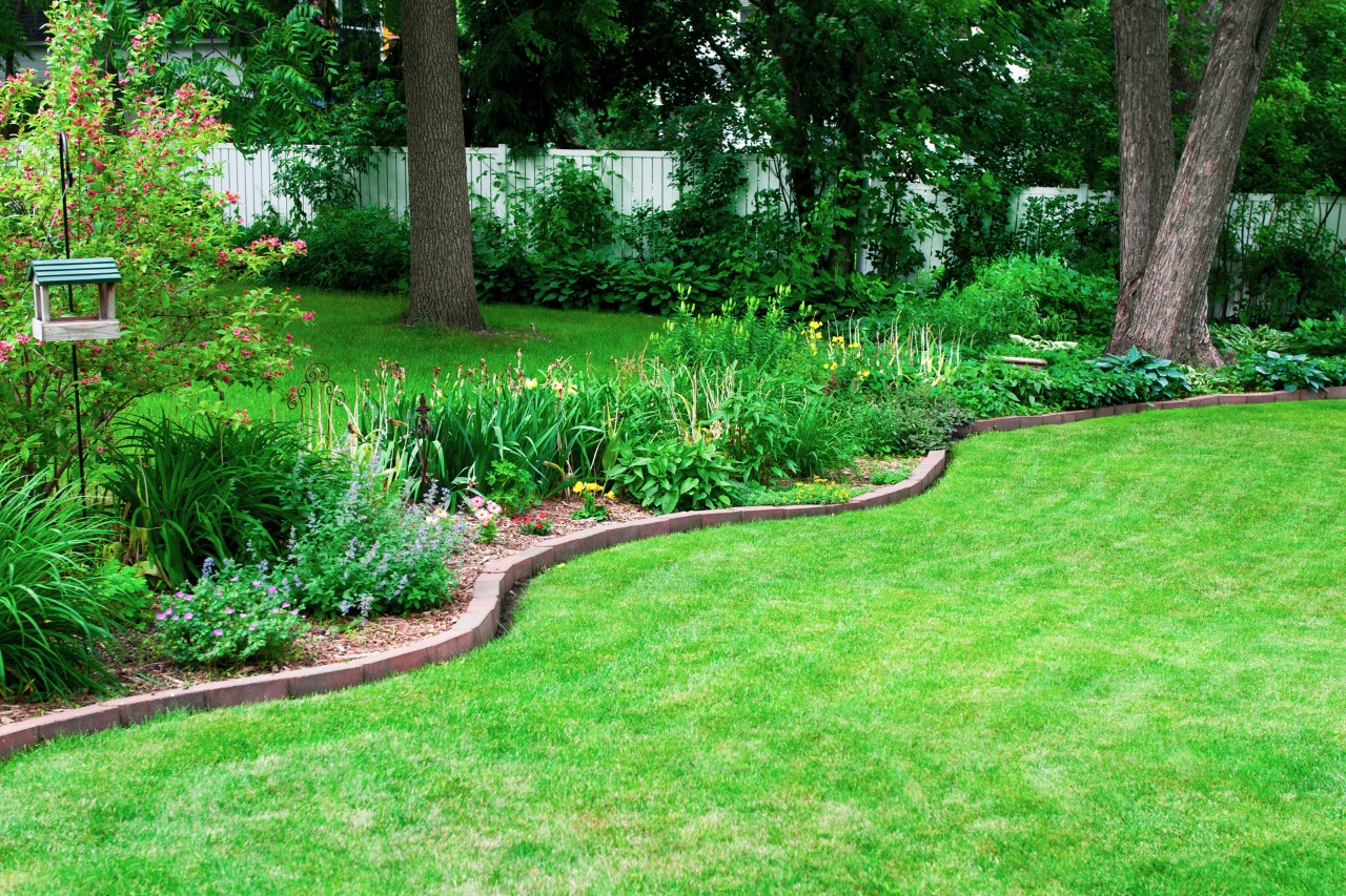 Plantenbed met een zelfgemaakte stenen border langs een groen gazon