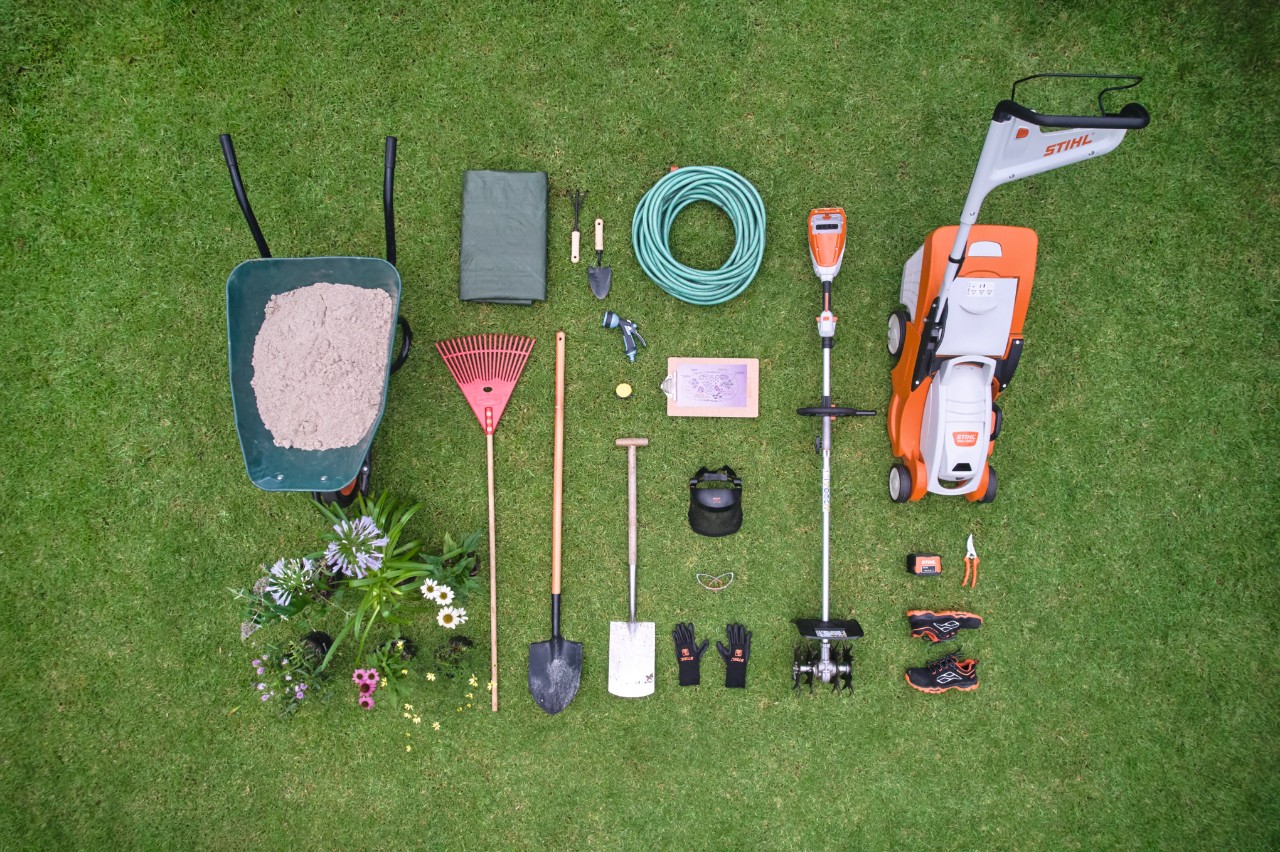 Gazon met gereedschap en materialen om een eilandperk aan te leggen, waaronder een STIHL RMA 339 C accugrasmaaier