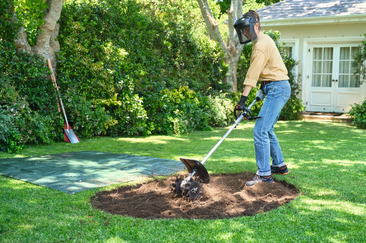 Een vrouw maakt de grond los voor een eilandperk met behulp van een STIHL combimotor met grondfrees 
