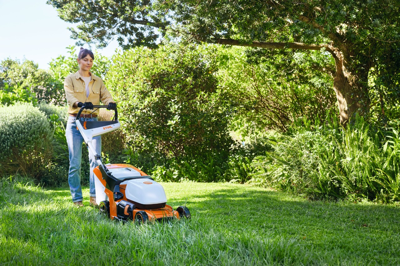 Een vrouw maait met een STIHL RMA 448 PV accugrasmaaier een stuk van het gazon
