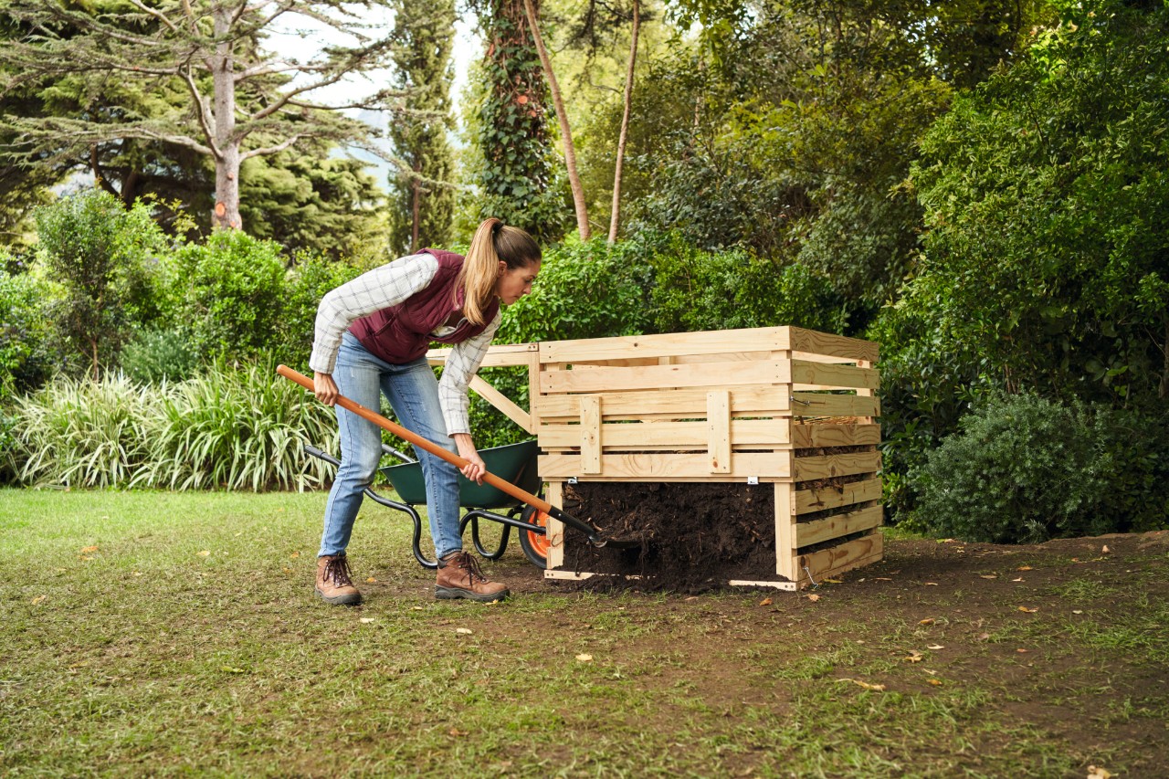 Een vrouw met een paardenstaart zet compost om met een schop
