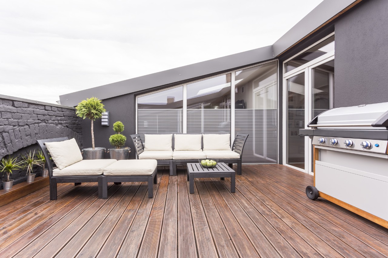 Tuinmeubelen, barbecue en planten op een dakterras met houten vloerbedekking