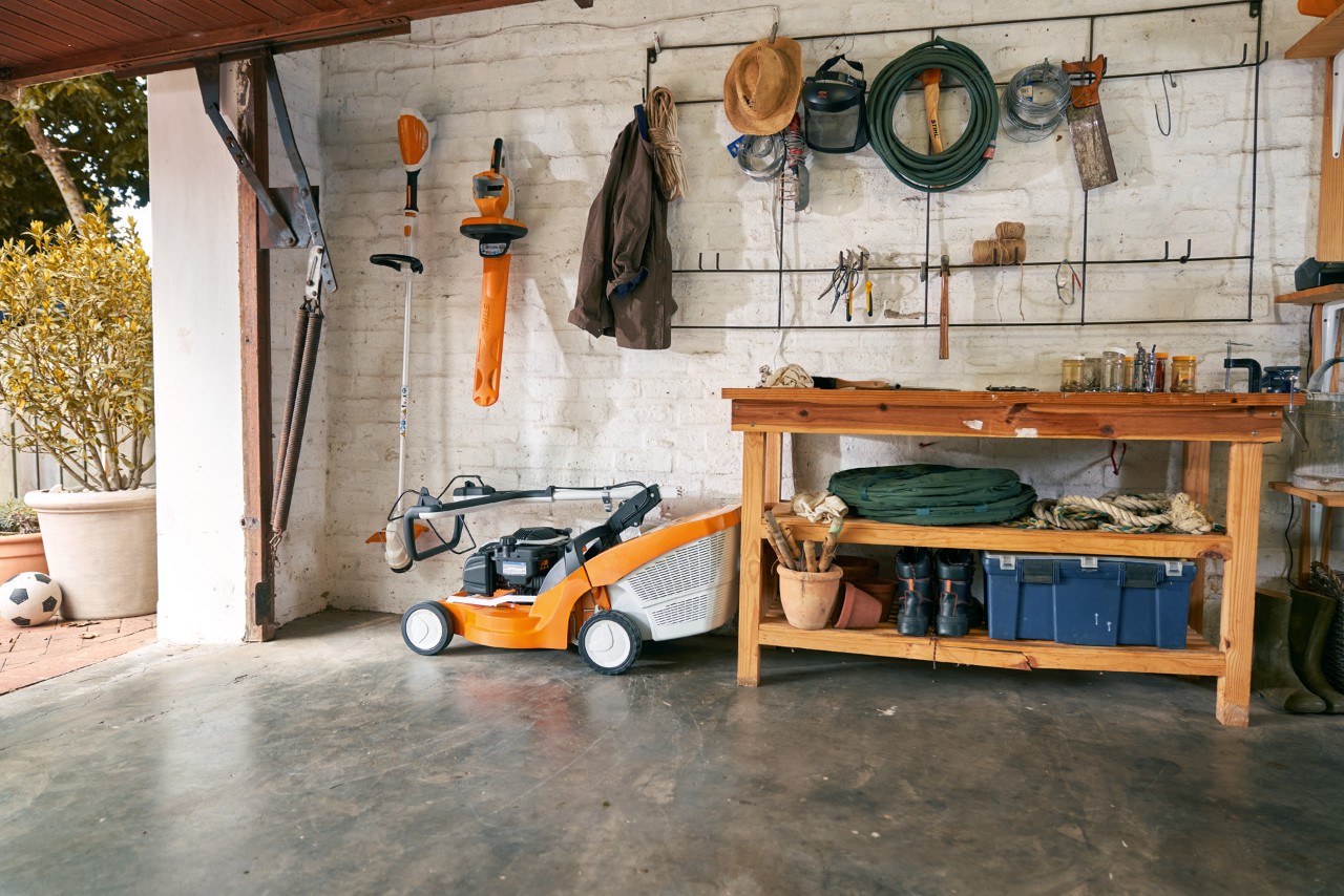Een STIHL RM 448 TC benzinegrasmaaier en ander elektrisch tuingereedschap netjes opgeborgen in een garage