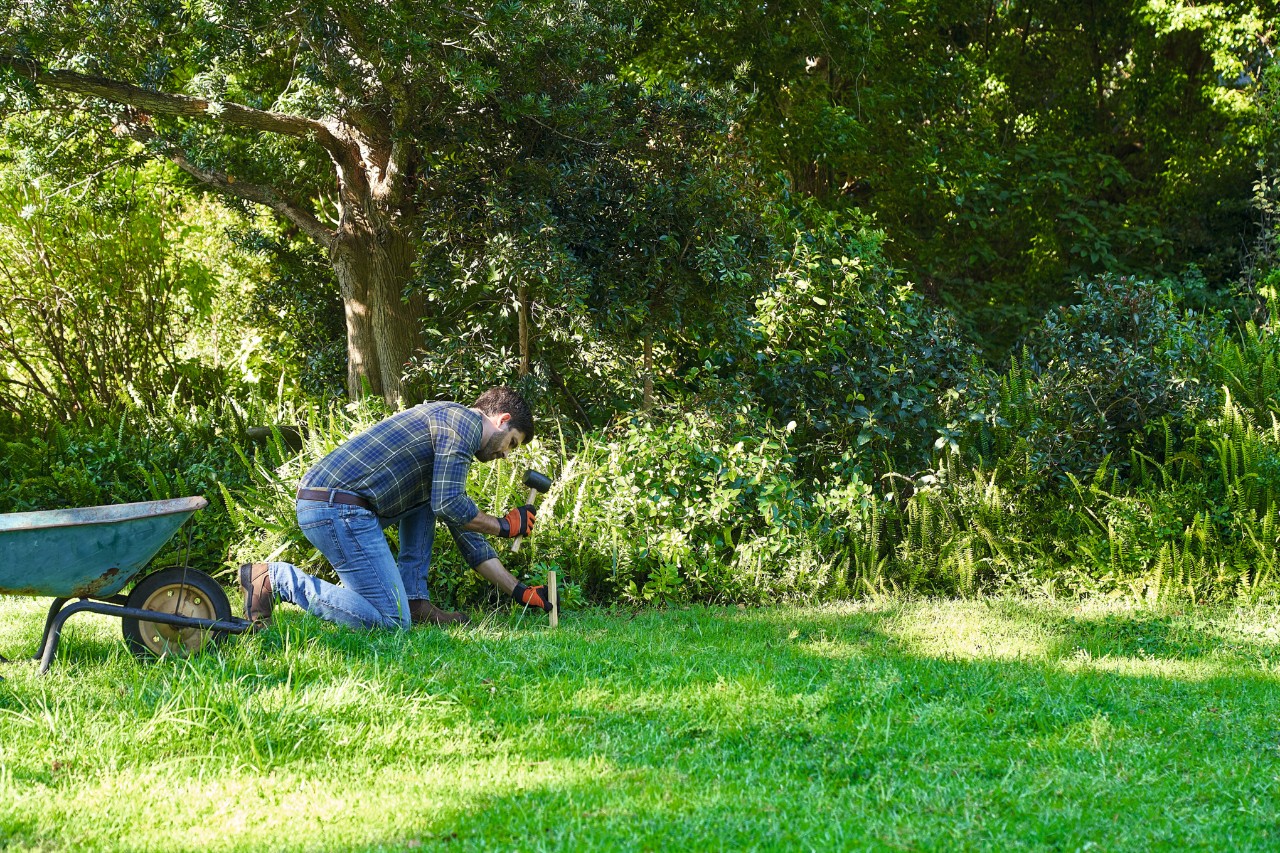 Een man markeert het oppervlak voor het aanleggen van een wilde bloemenweide met waslijn en paaltjes