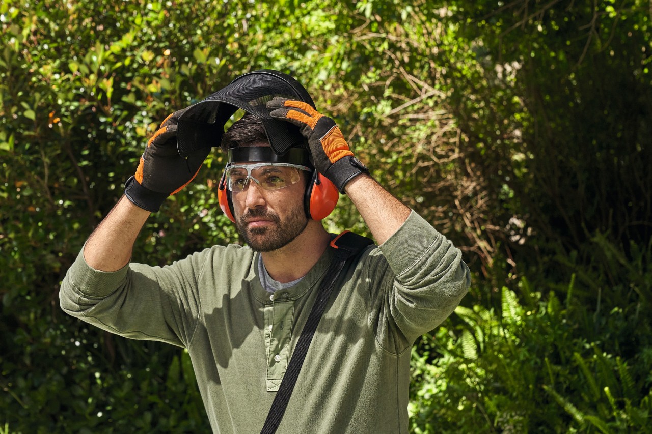 Een man in STIHL veiligheidsuitrusting in een tuin 